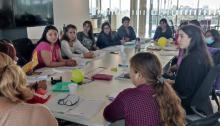 Varias personas reunidas alrededor de una mesa, conversando y compartiendo ideas en un ambiente colaborativo.